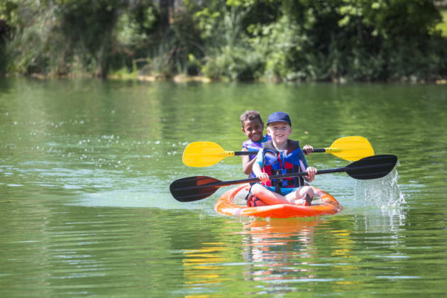 Two people paddling in a kayak on a lake.