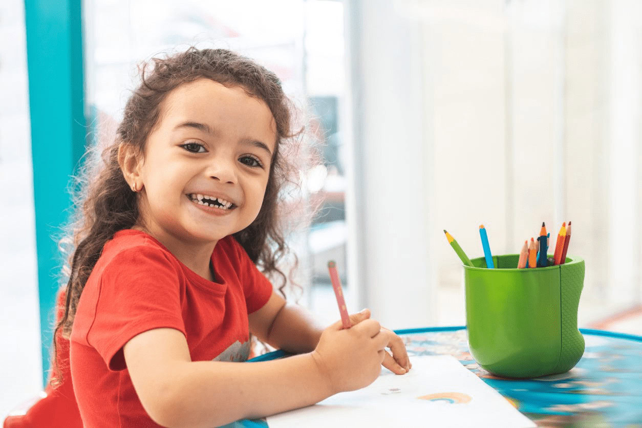 A little girl is sitting at a table and drawing.
